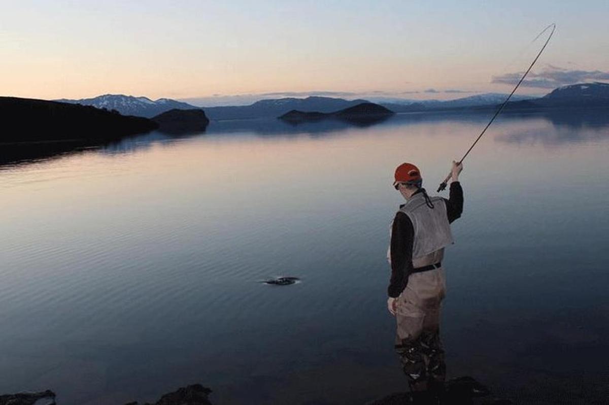 seorang lelaki memegang pancing di tasik