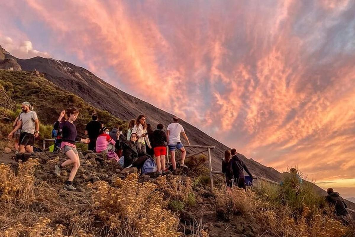 um grupo de pessoas em pé em uma colina ao pôr do sol
