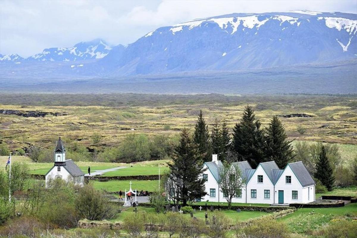 a white house in a field with mountains in the background