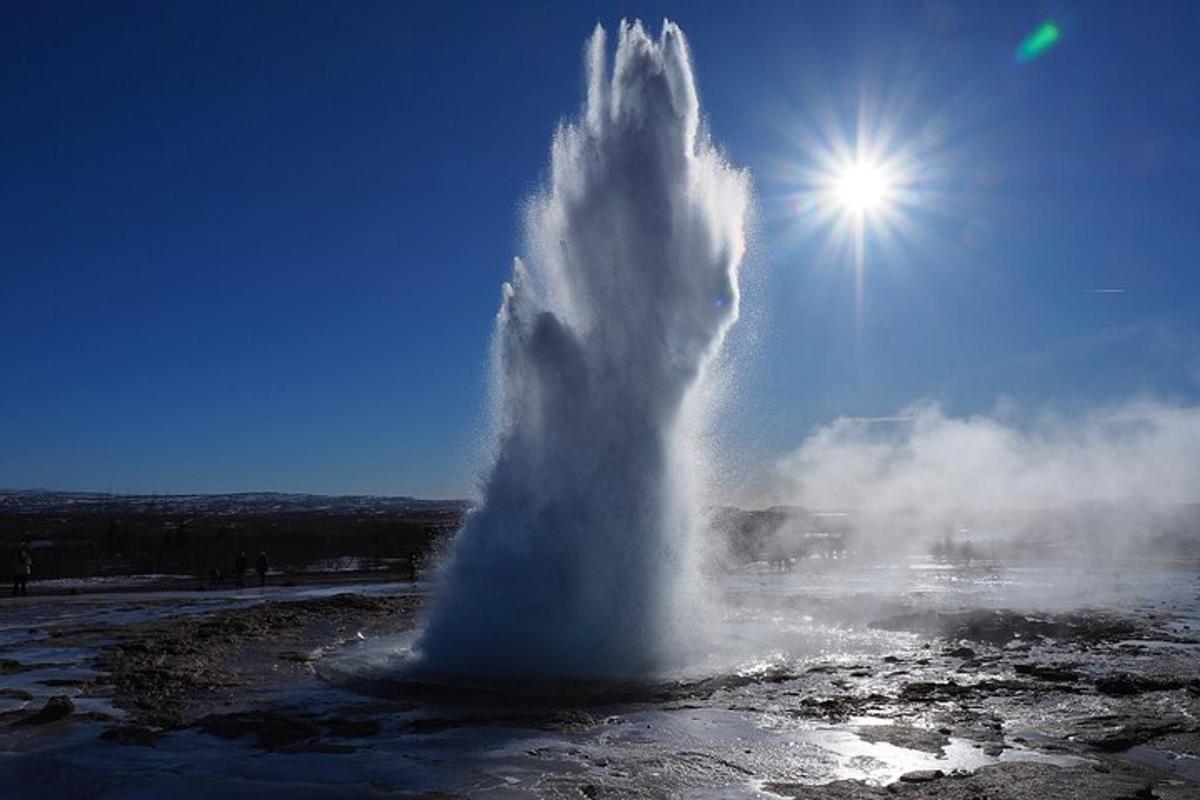 en geysir i vannet med solen bak seg