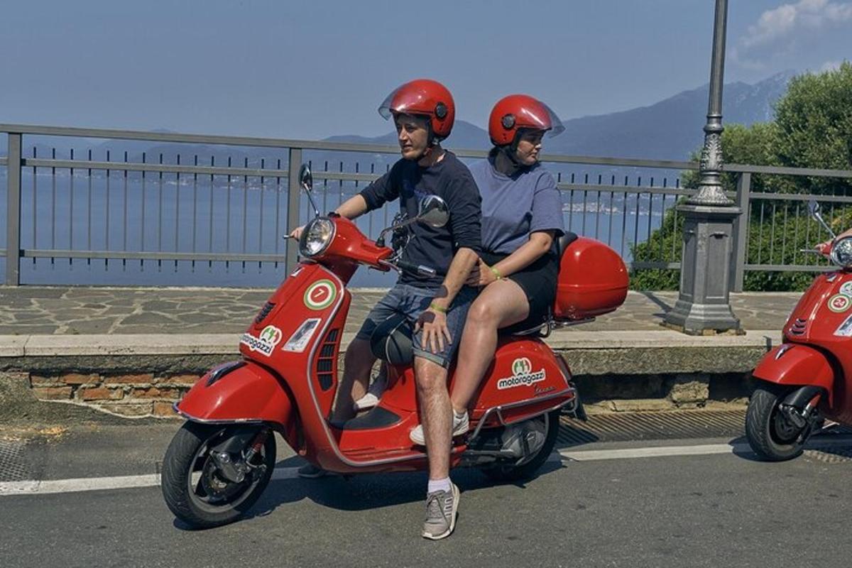 due uomini che indossano caschi seduti su uno scooter rosso