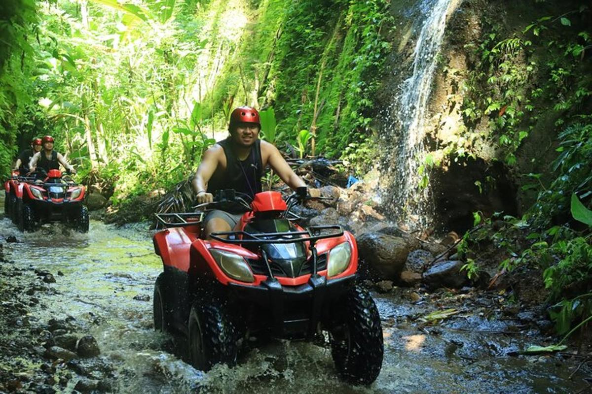 dua pria mengendarai ATV melalui sungai di air terjun