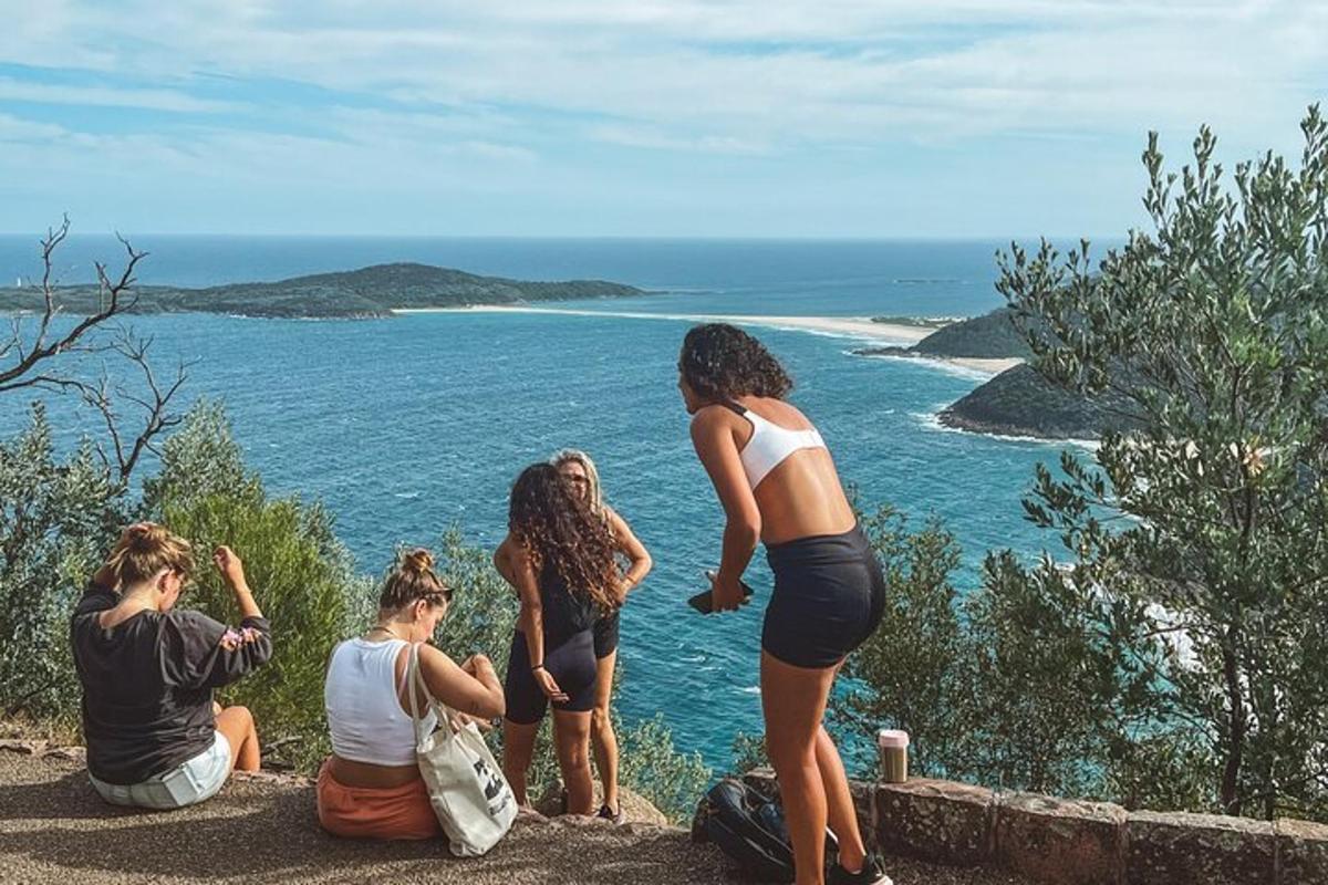 a group of women sitting on a hill looking at the ocean