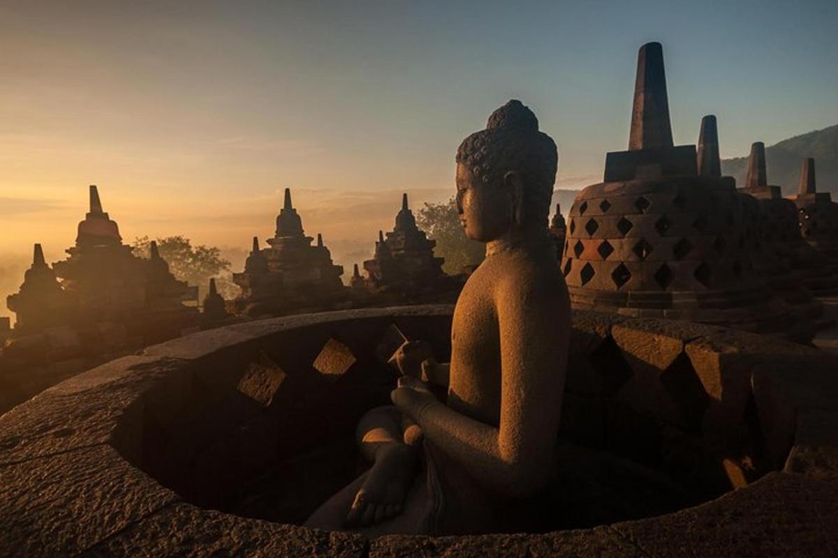 a statue sitting on top of a building with a sunset in the background
