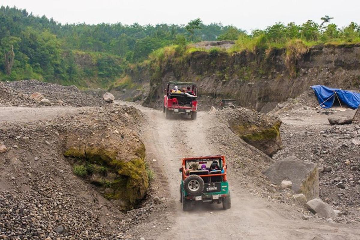 two dump trucks driving down a dirt road