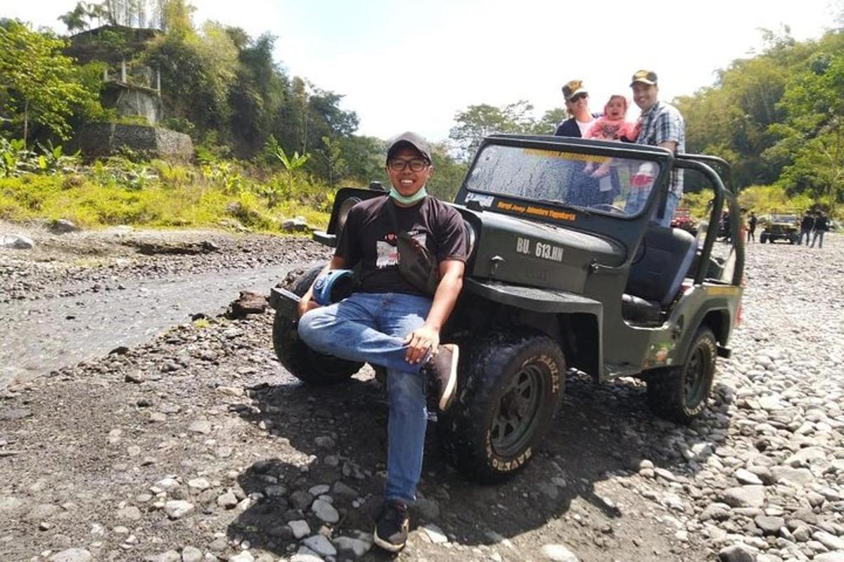 a man sitting next to a jeep on a rocky road