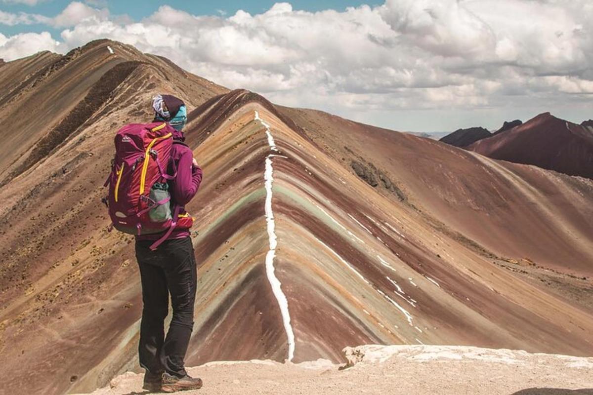 seseorang dengan beg galas berdiri di atas gunung