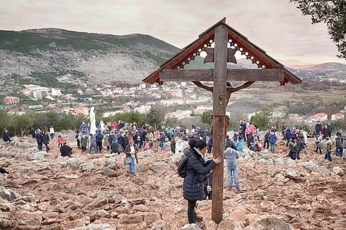 Una multitud de personas de pie alrededor de una cruz de madera