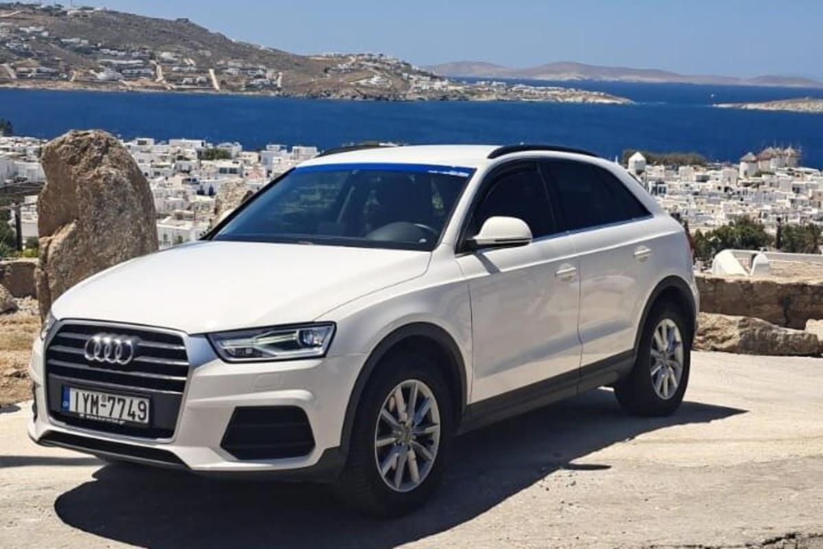 a white audi suv parked in front of a city