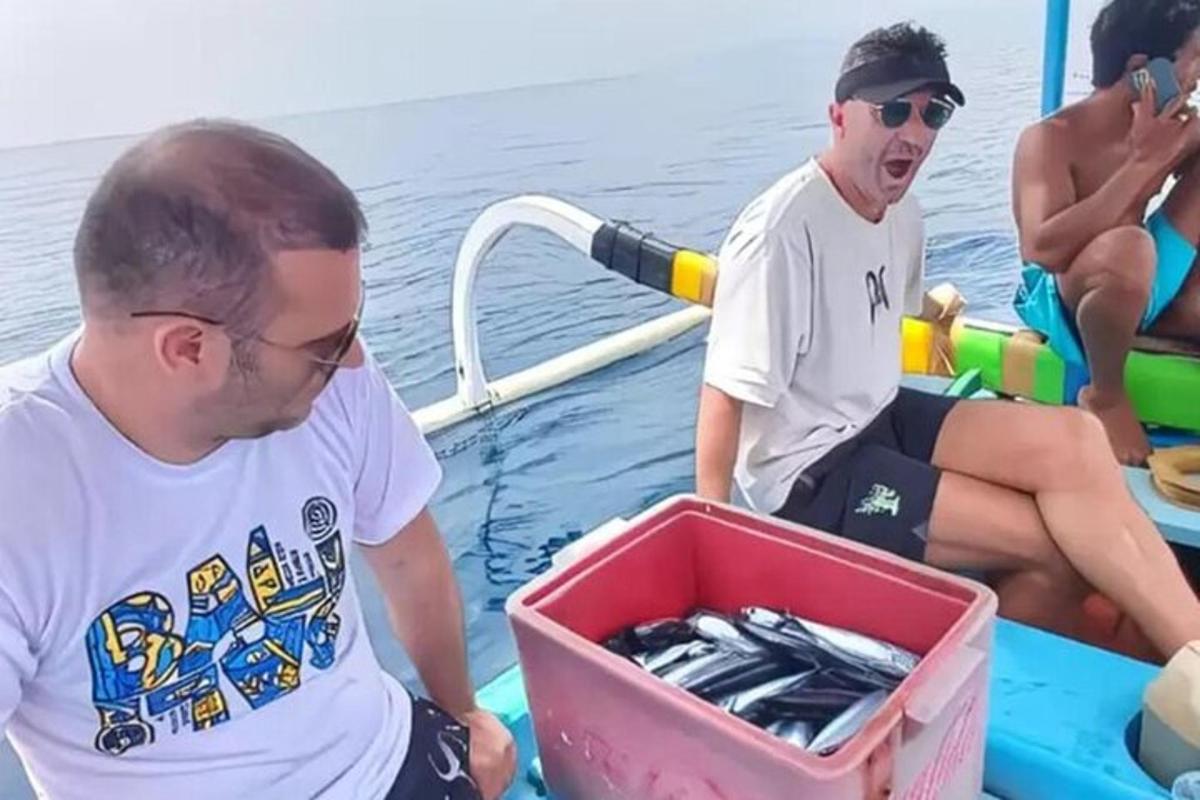 two men on a boat with a box of fish