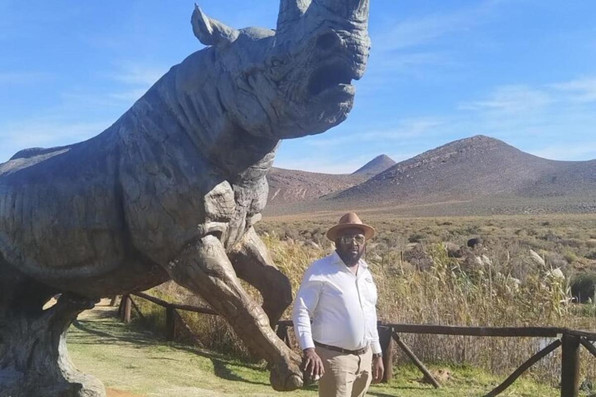 en mann som står foran en statue av en dinosaur