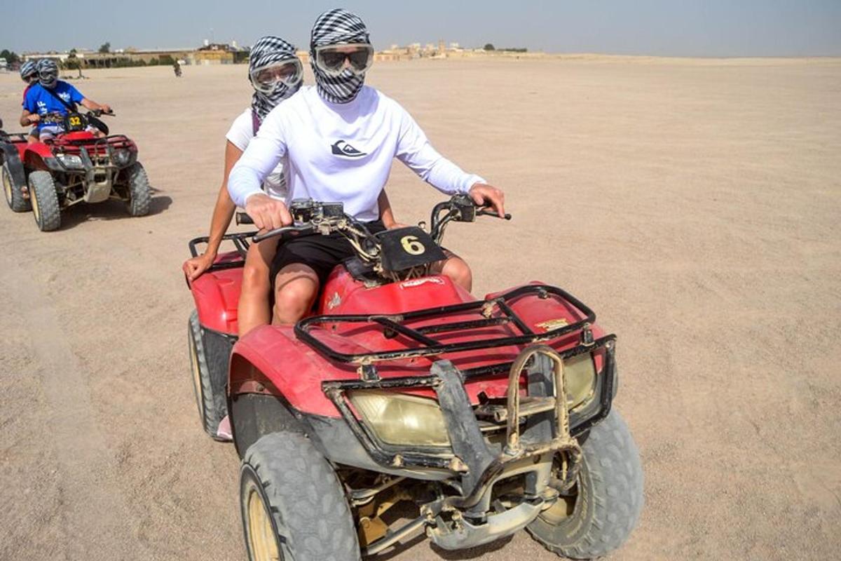 duas pessoas andando de quadriciclo no deserto