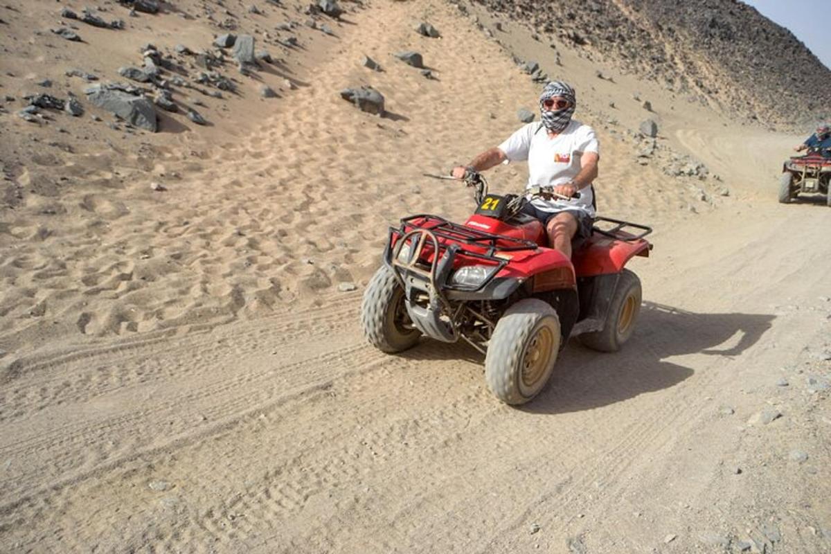 um homem andando de quadriciclo no deserto