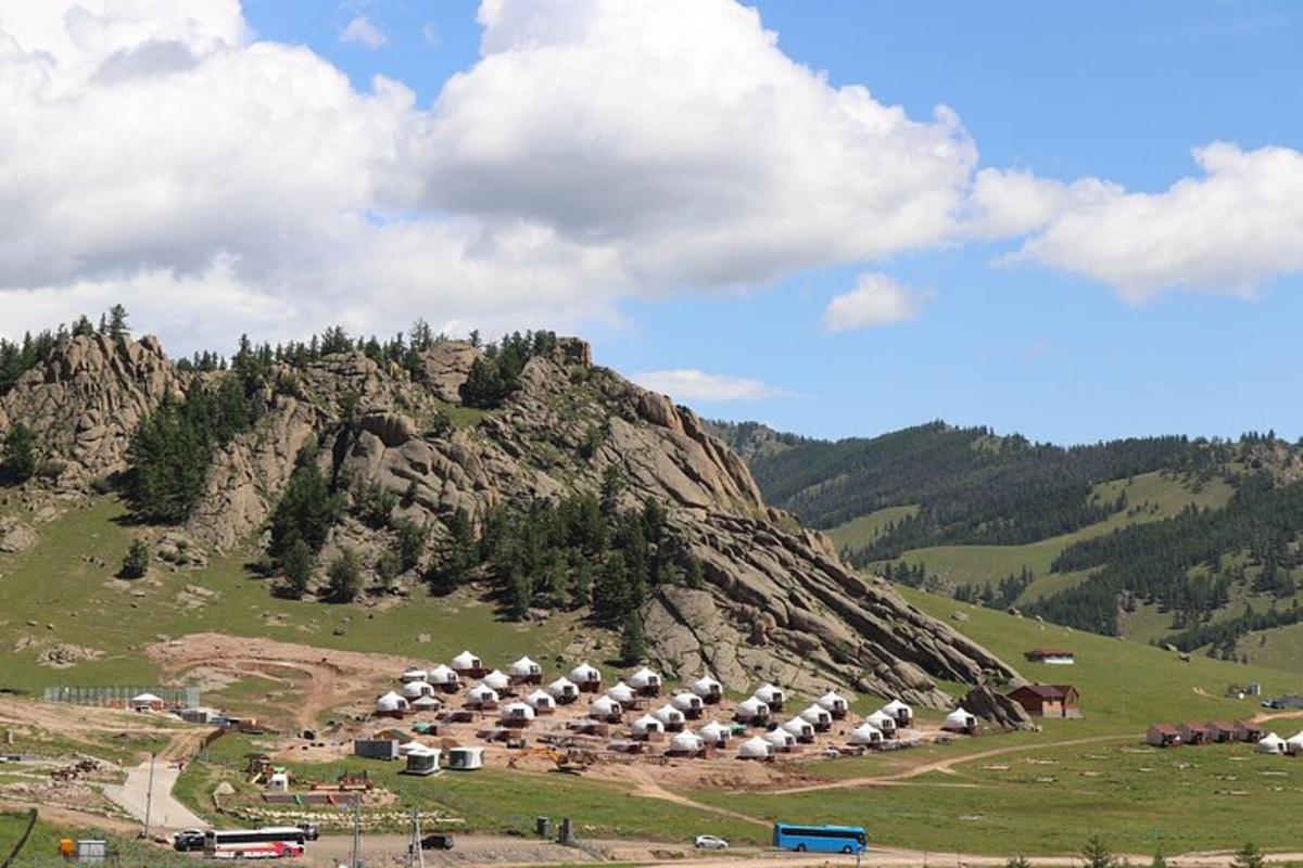 a group of tents on a hill in front of a mountain
