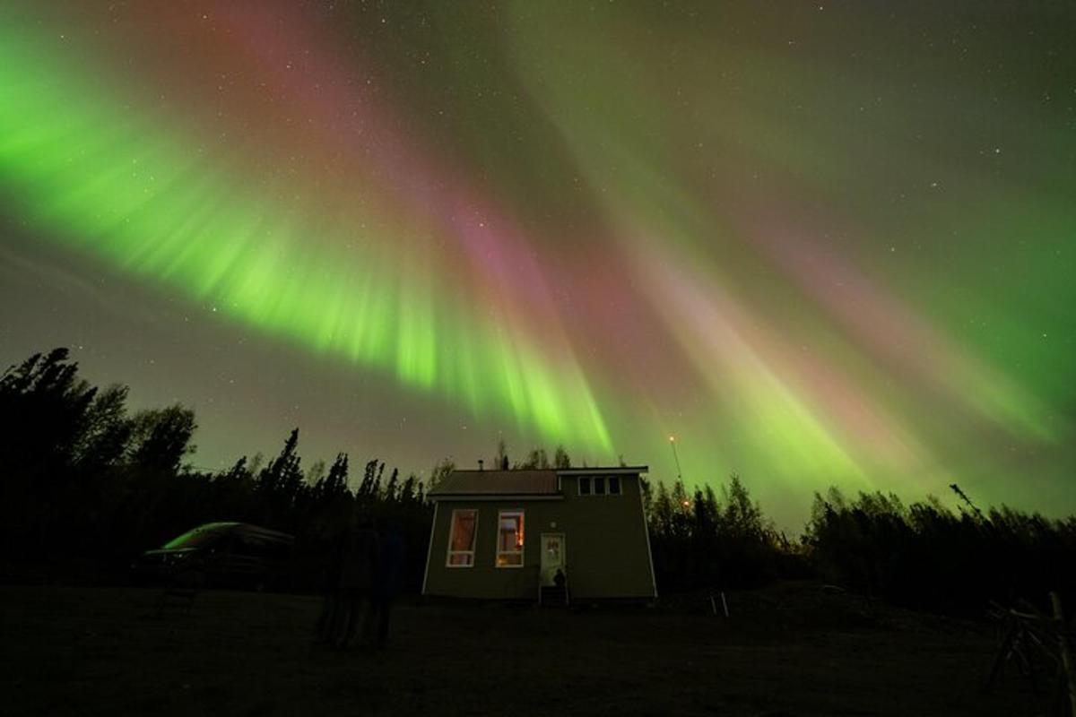 una casa con le luci dell'aurora nel cielo