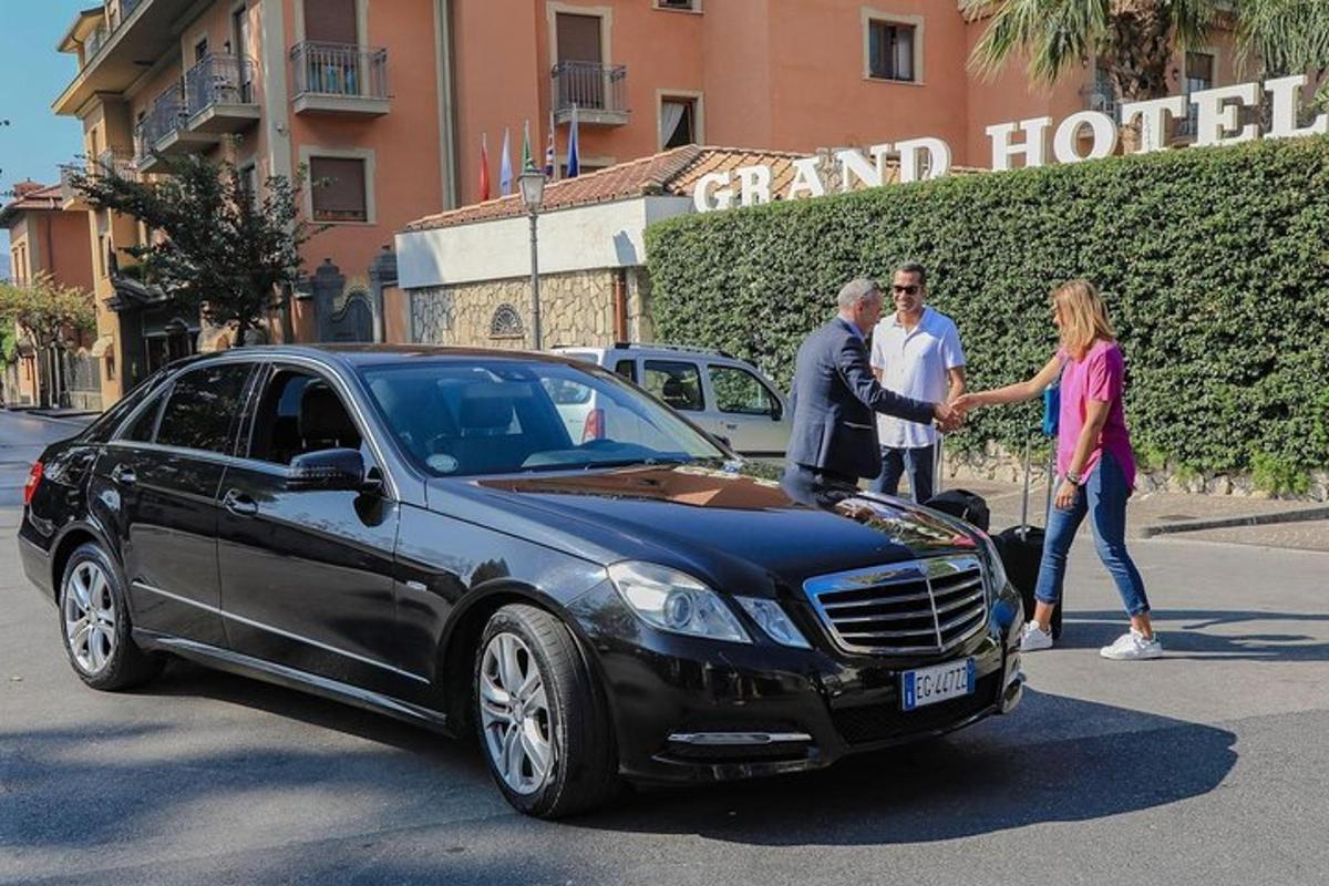 μια ομάδα ανθρώπων που στέκονται δίπλα σε ένα μαύρο αυτοκίνητο