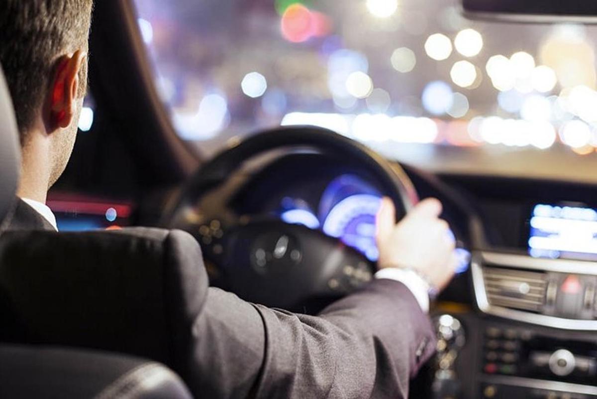 ένας άντρας με κοστούμι οδηγεί ένα αυτοκίνητο