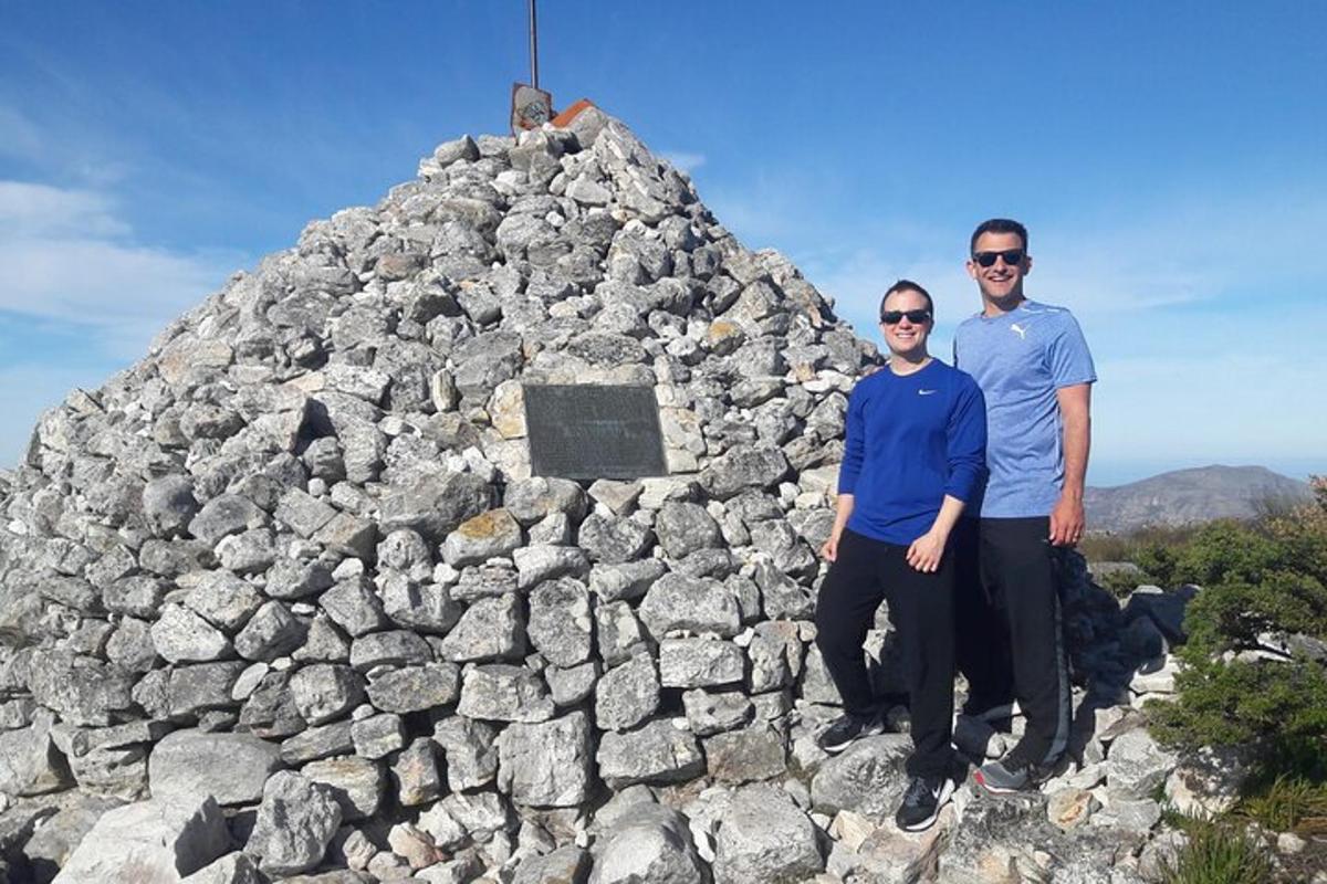 dva lidé stojící před skalní pyramidou