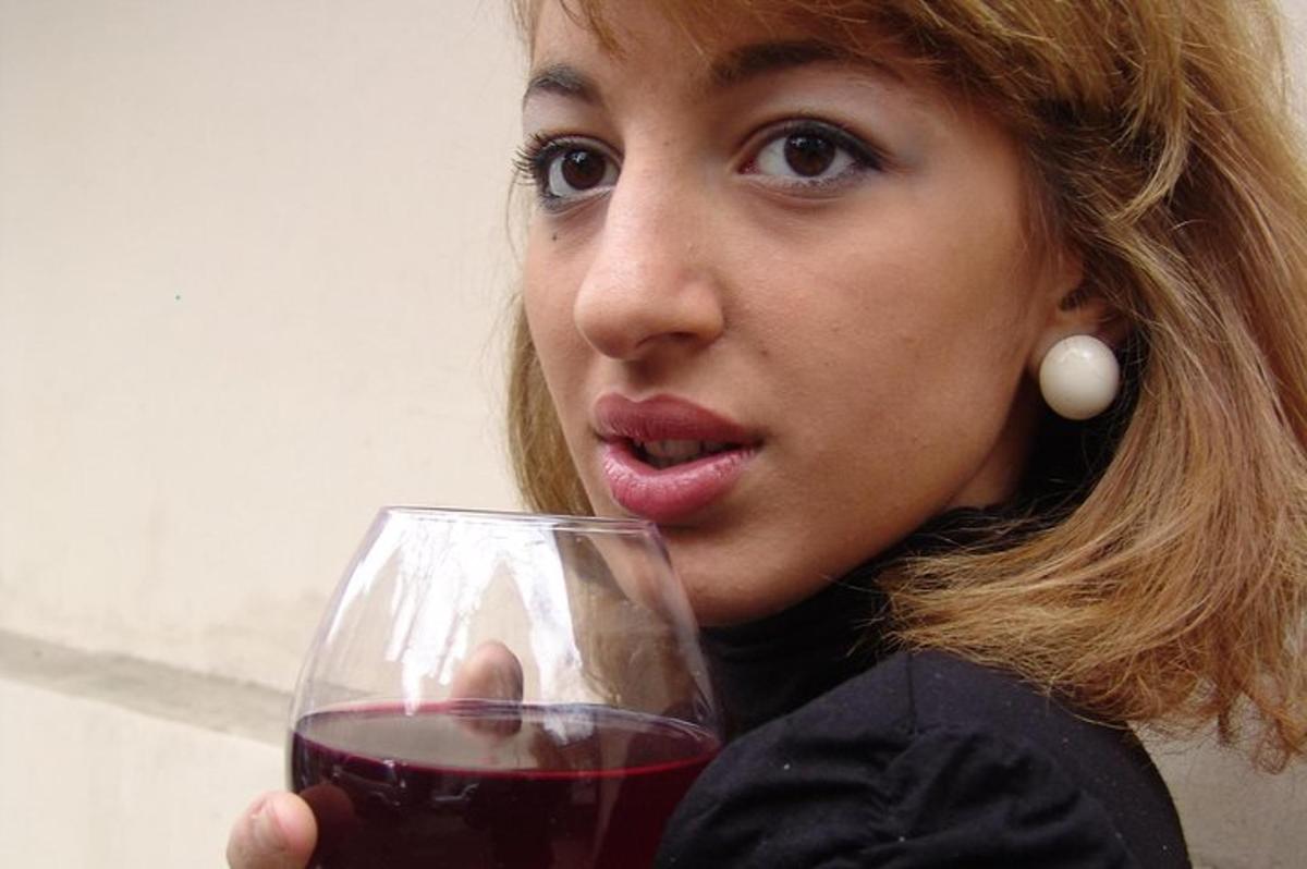 una donna che tiene in mano un bicchiere di vino rosso