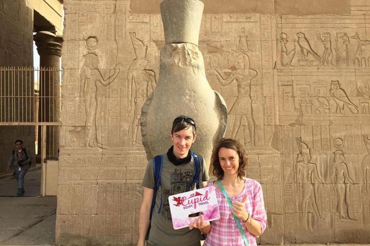 un uomo e una donna che tengono un cartello davanti a una statua