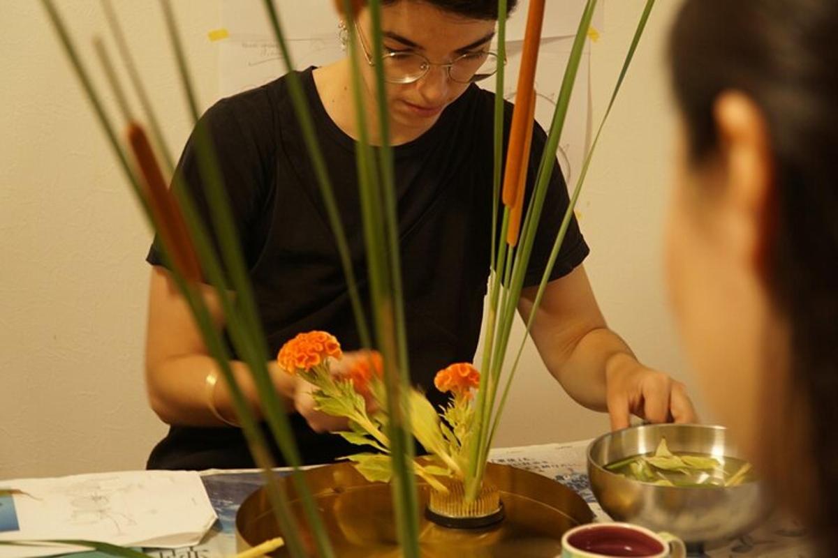 en kvinne arrangerer blomster i en vase på et bord