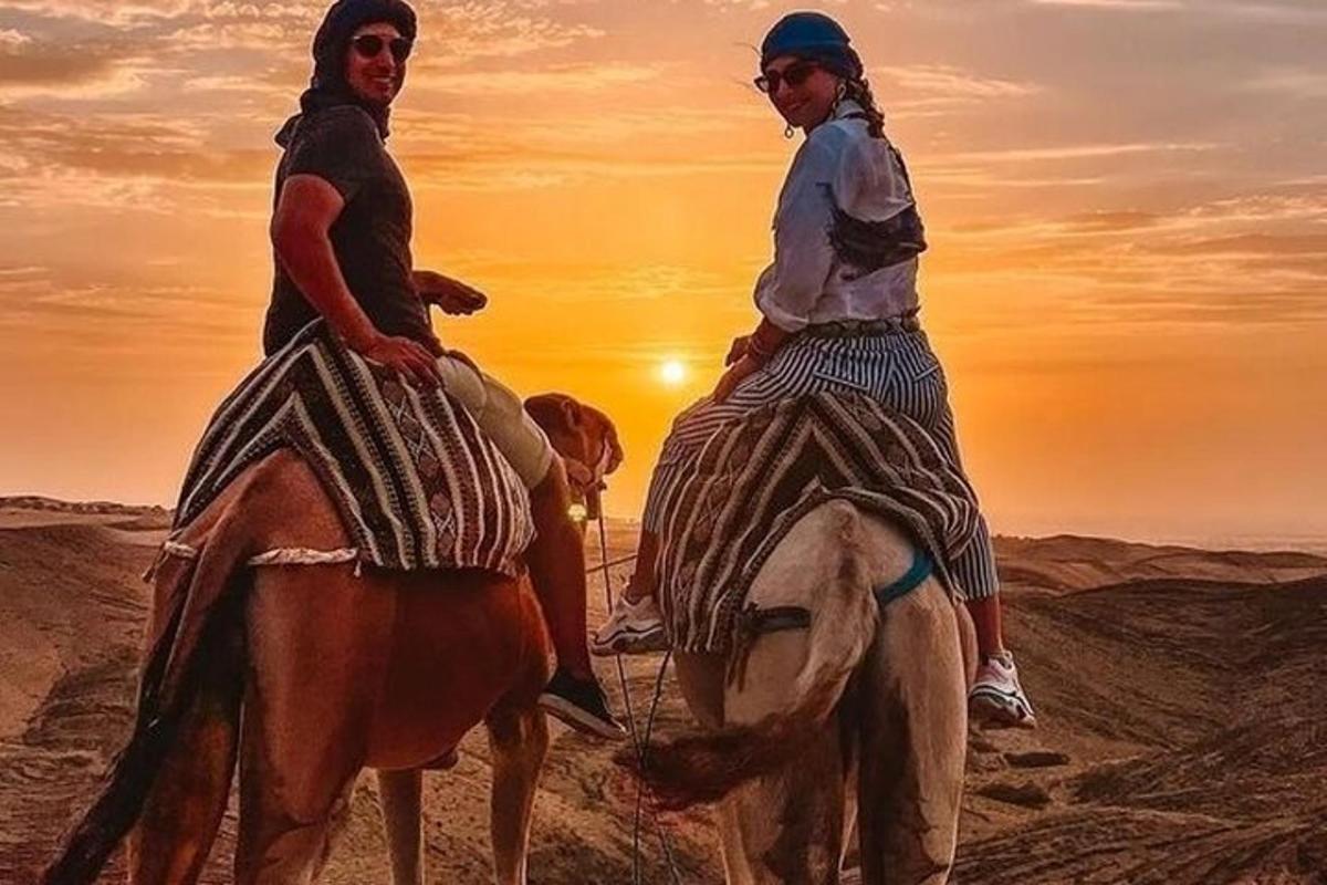 two women riding horses in the desert at sunset