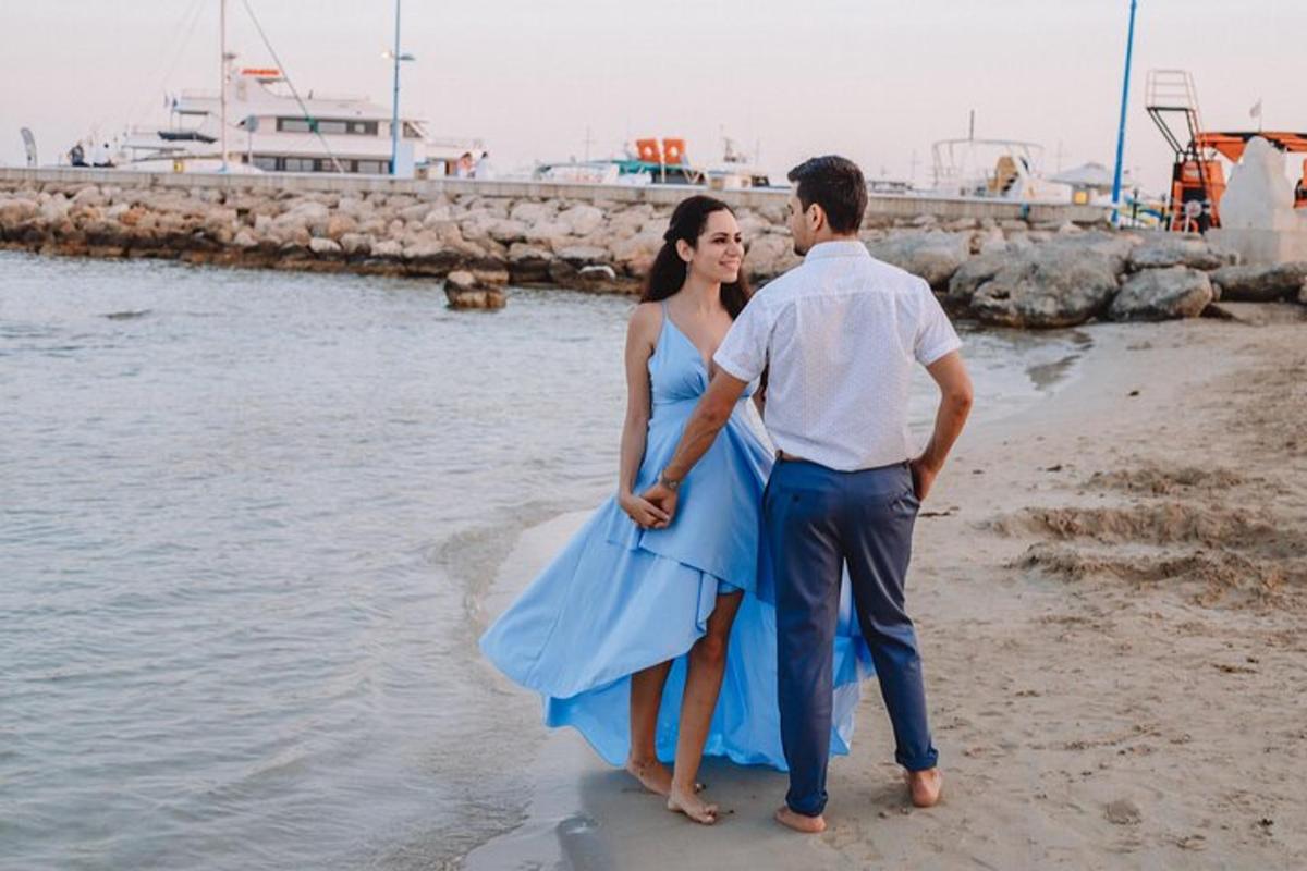 um homem e uma mulher de vestido azul em pé na praia