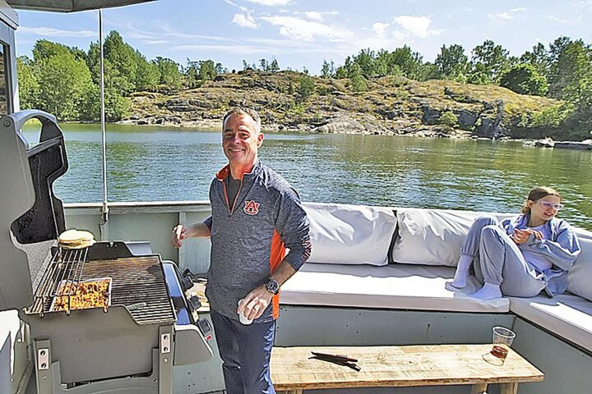 um homem em pé na parte de trás de um barco com uma grelha