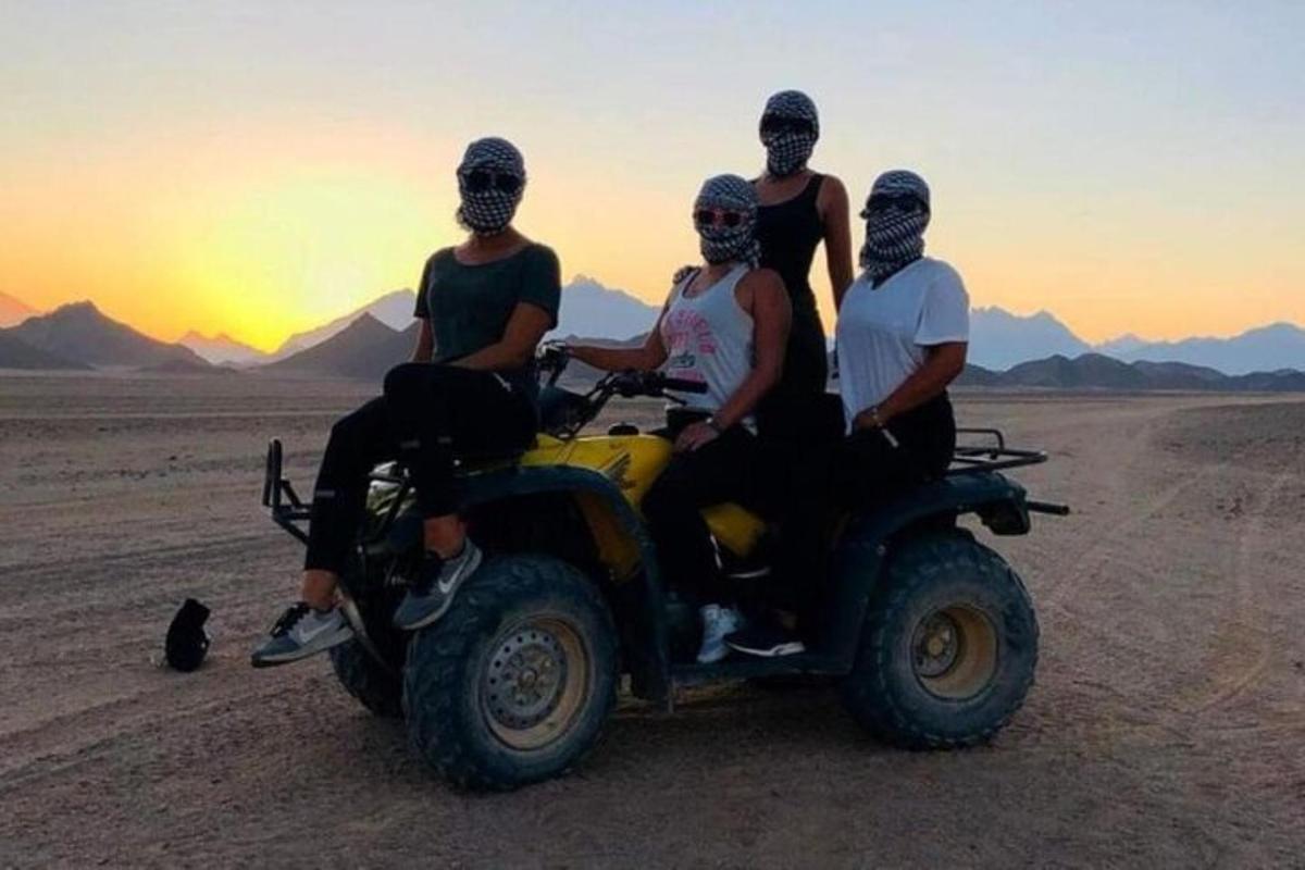 Un grupo de personas sentadas en un vehículo de cuatro ruedas en el desierto.
