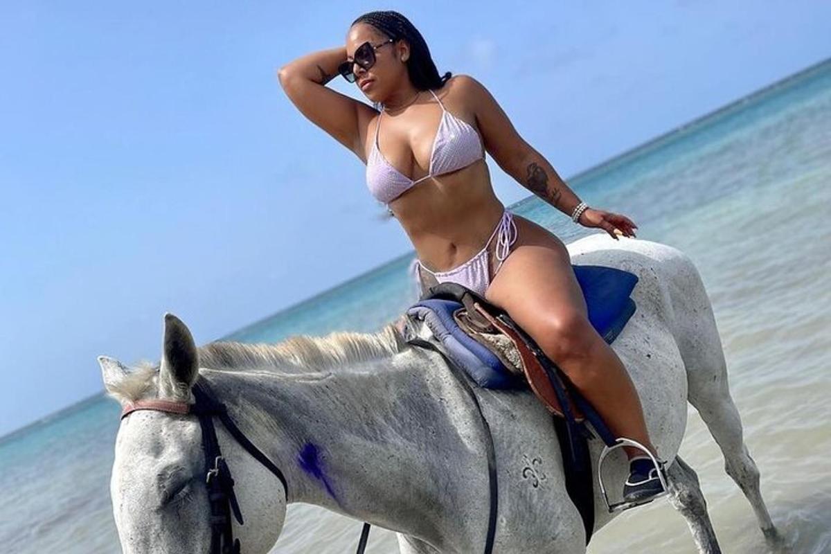 o femeie în bikini călare pe un cal pe plajă