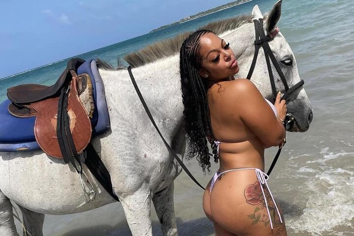 ženska v bikiniju stoji poleg konja na plaži