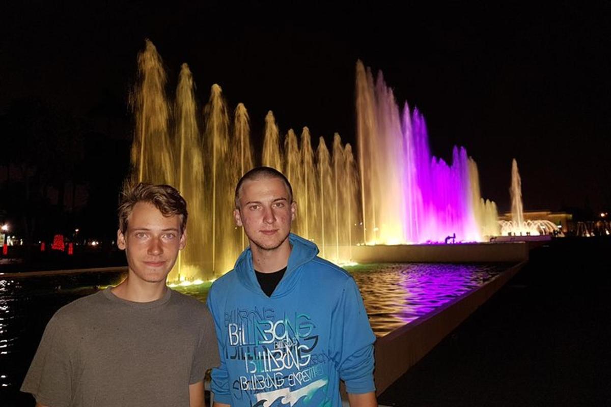 dva muži stojící v noci před fontánou