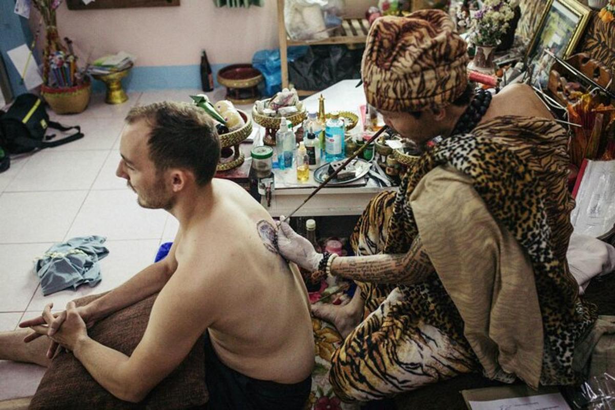 un uomo a torso nudo che si fa un tatuaggio sul braccio di un uomo