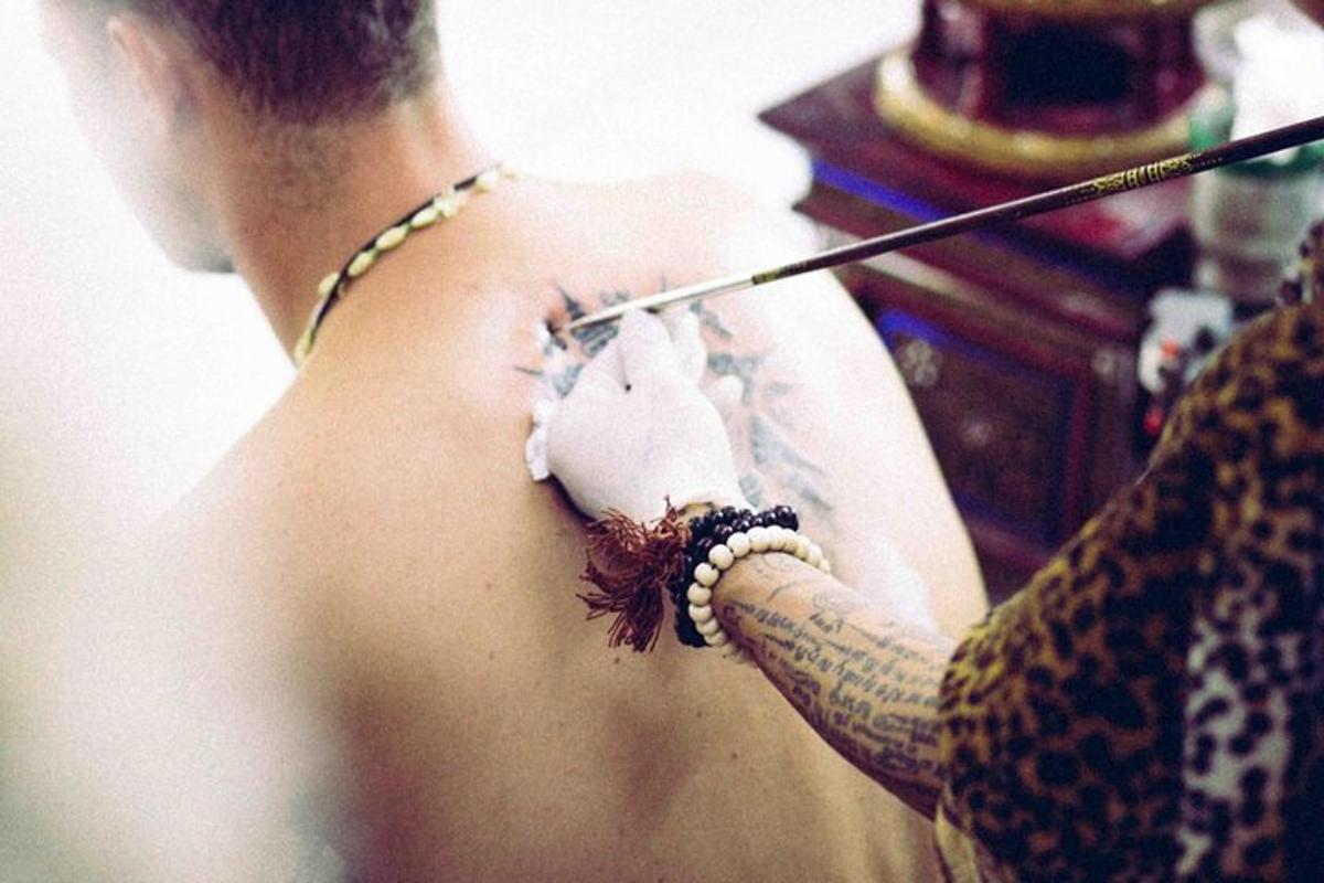un uomo con un tatuaggio sulla spalla che tiene in mano un ago
