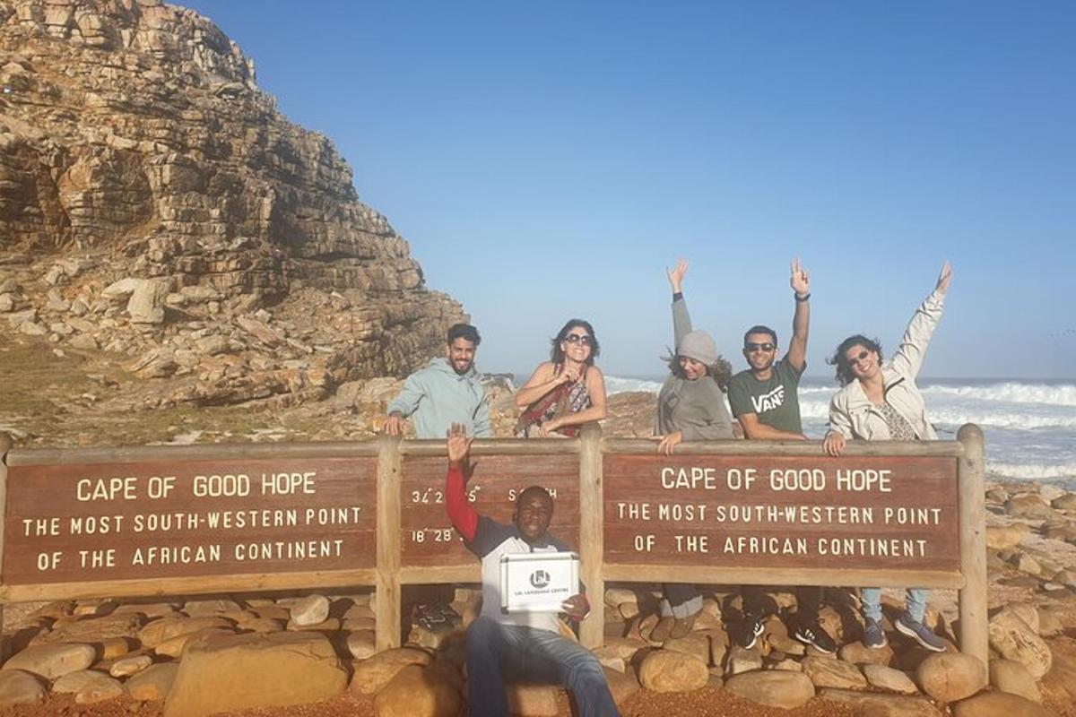 a group of people standing behind a sign on the beach