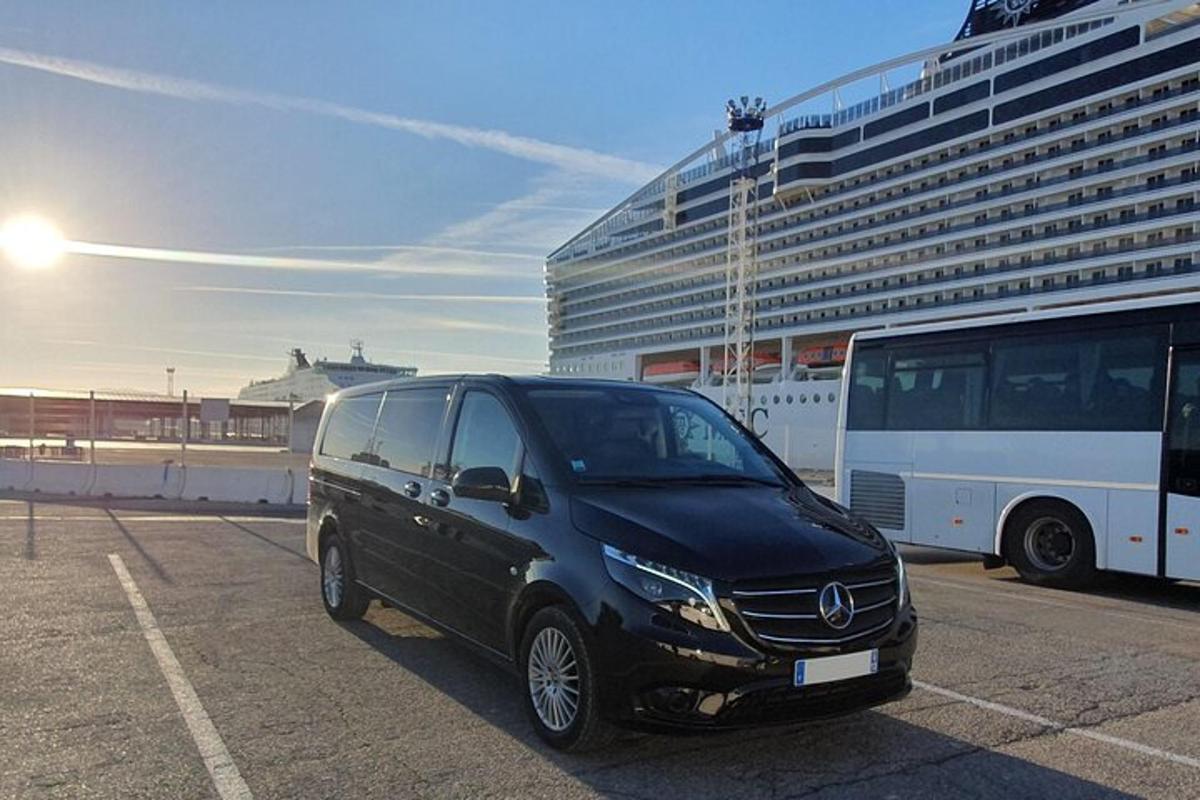 a black van parked in a parking lot next to a cruise ship