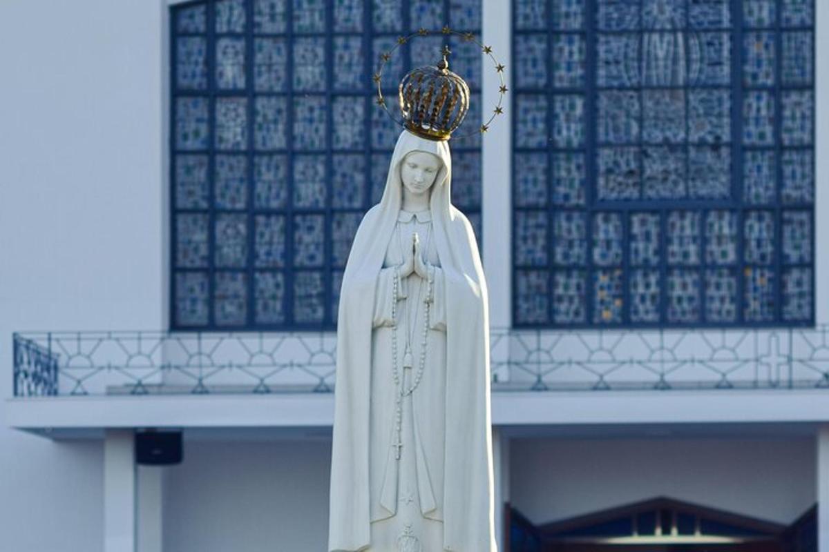 una statua di una suora in piedi davanti a un edificio