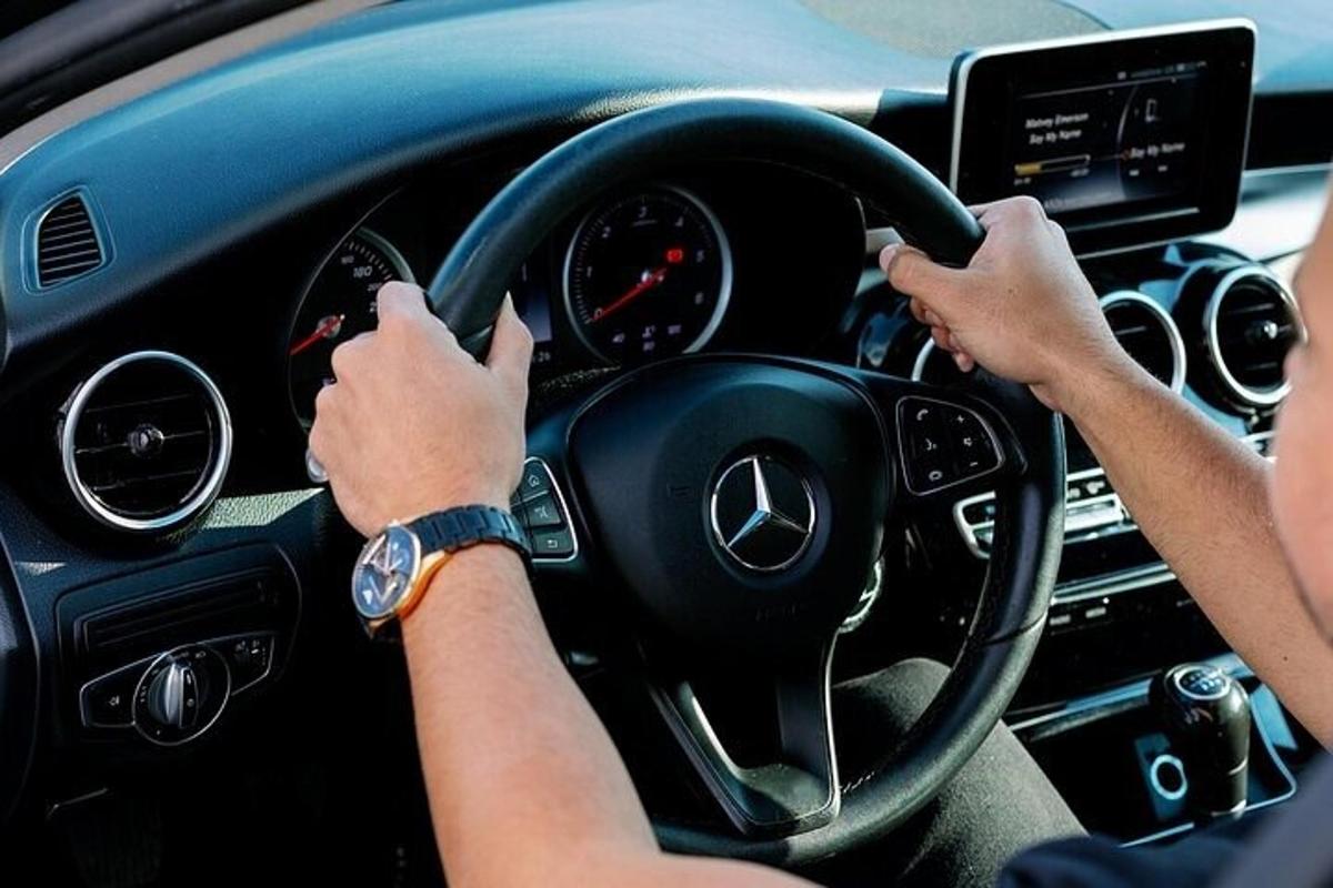 osoba řídící auto s rukama na volantu
