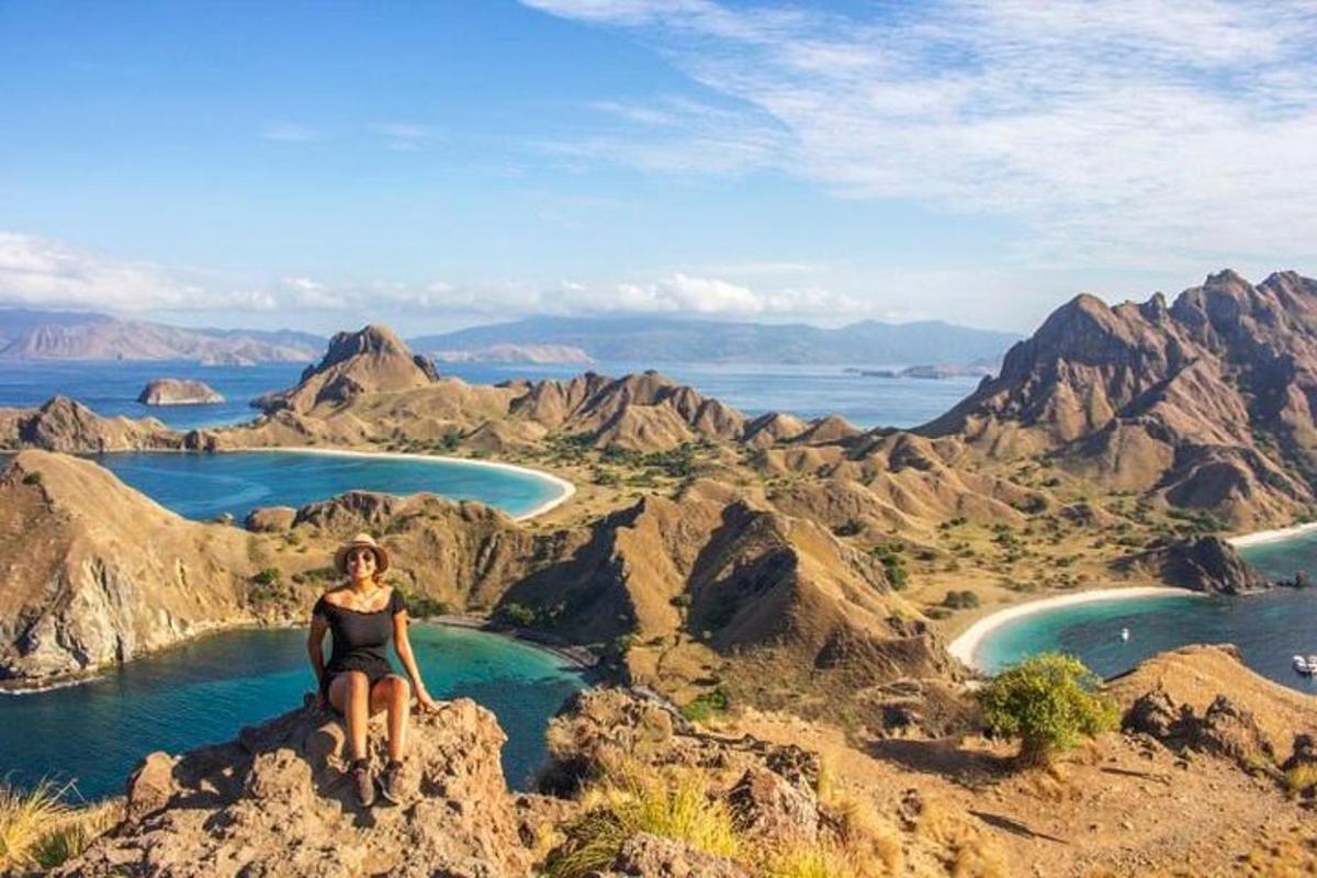 seorang wanita duduk di atas batu yang menghadap ke pantai