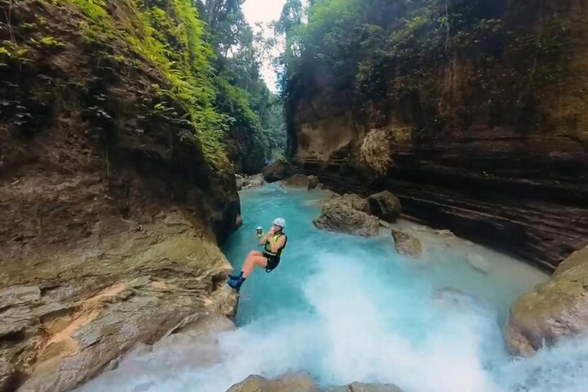 una persona saltando de una cascada a un río