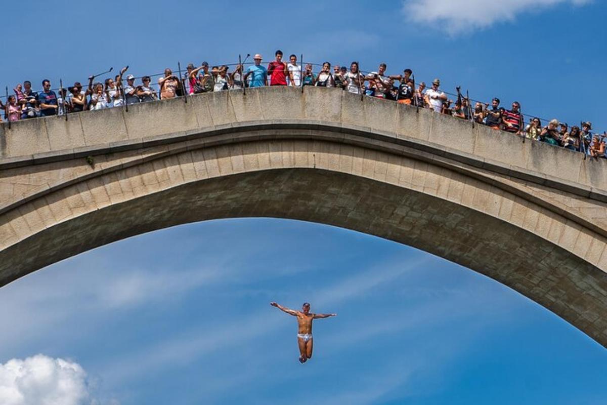 Un hombre parado en lo alto de un puente con una multitud.