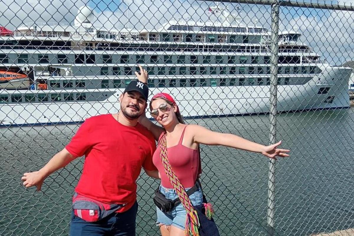 een man en vrouw staan voor een hek met een cruiseschip