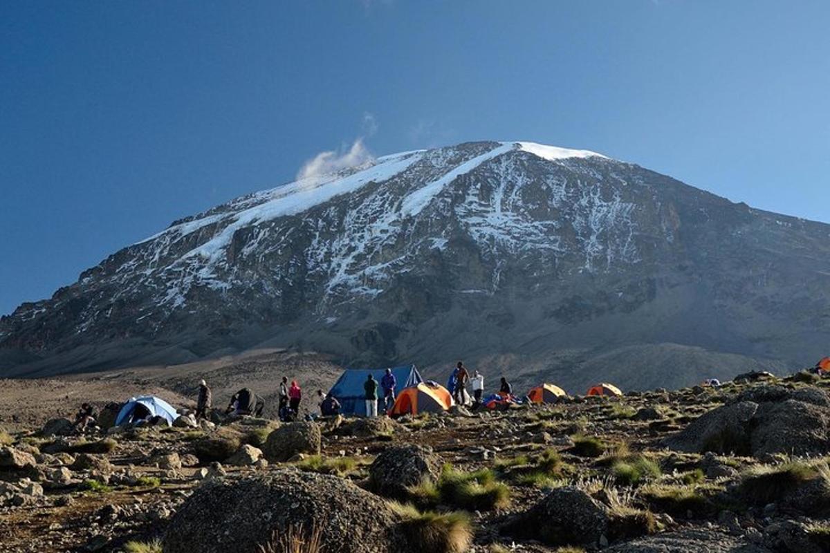 hópur fólks stendur umhverfis fjall með tjöldum