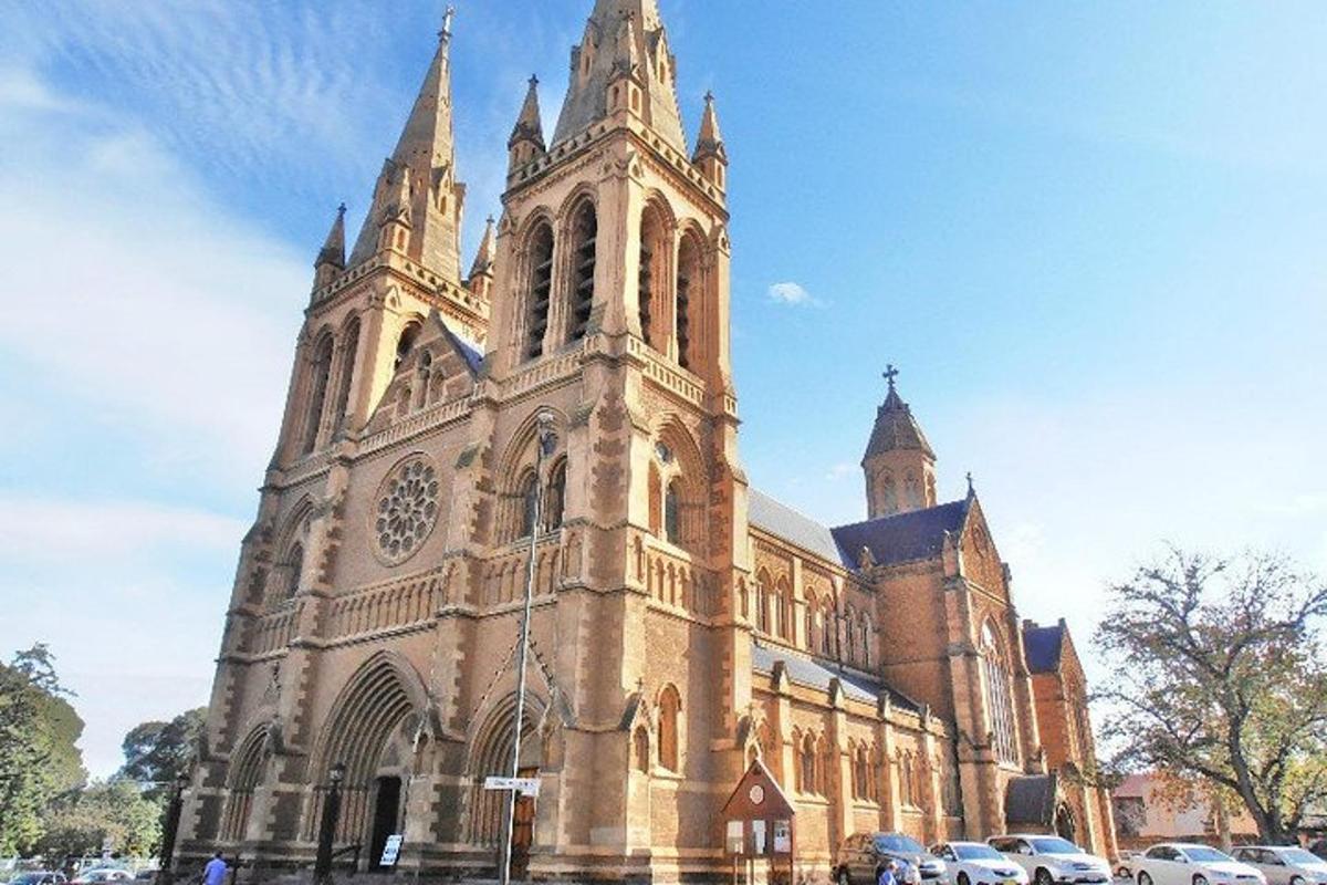 Una gran iglesia con coches aparcados delante de ella.