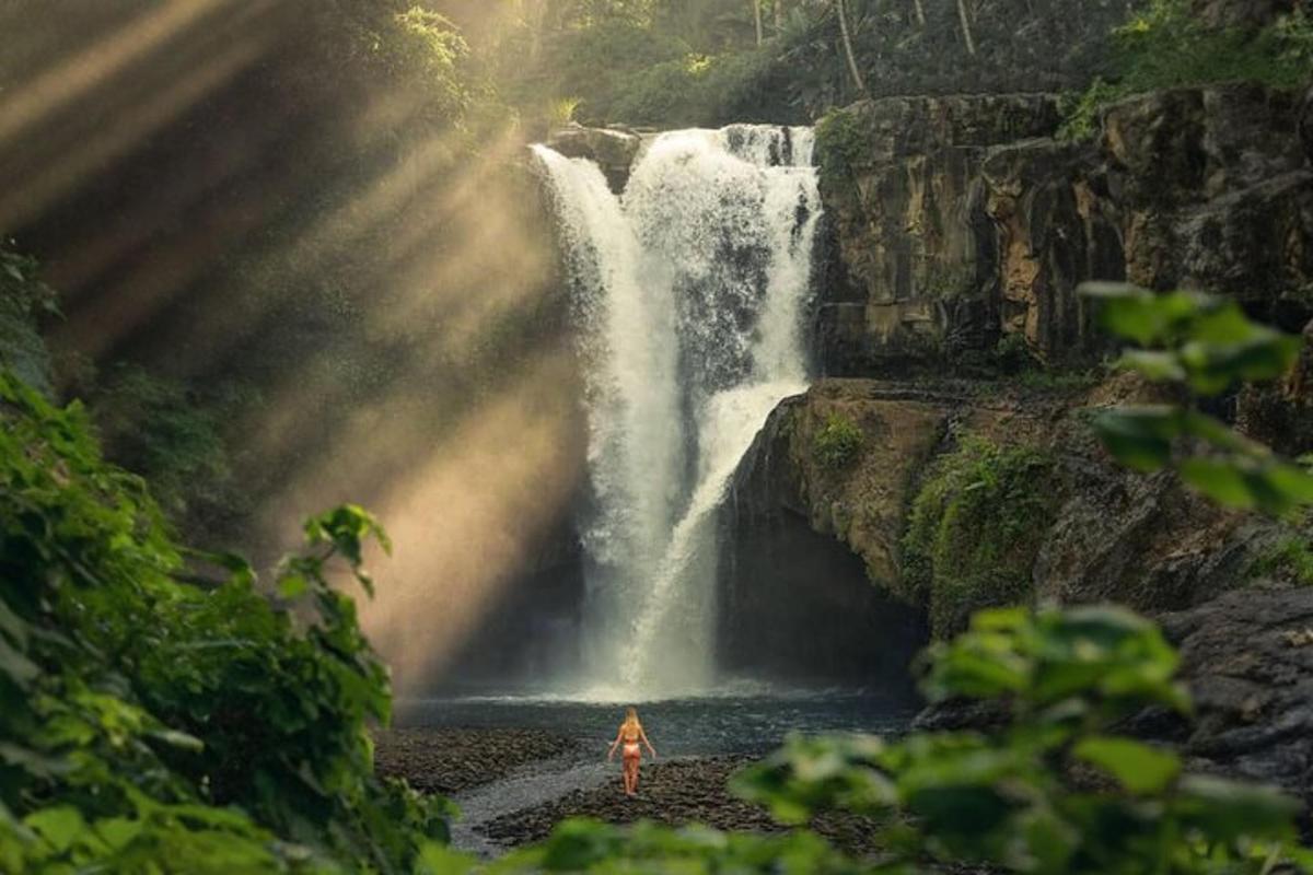 a woman standing in front of a waterfall