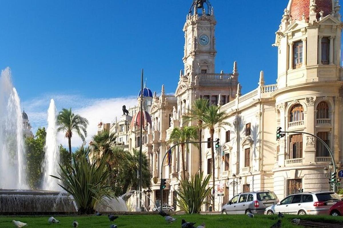 Un gran edificio con una torre de reloj y una fuente.