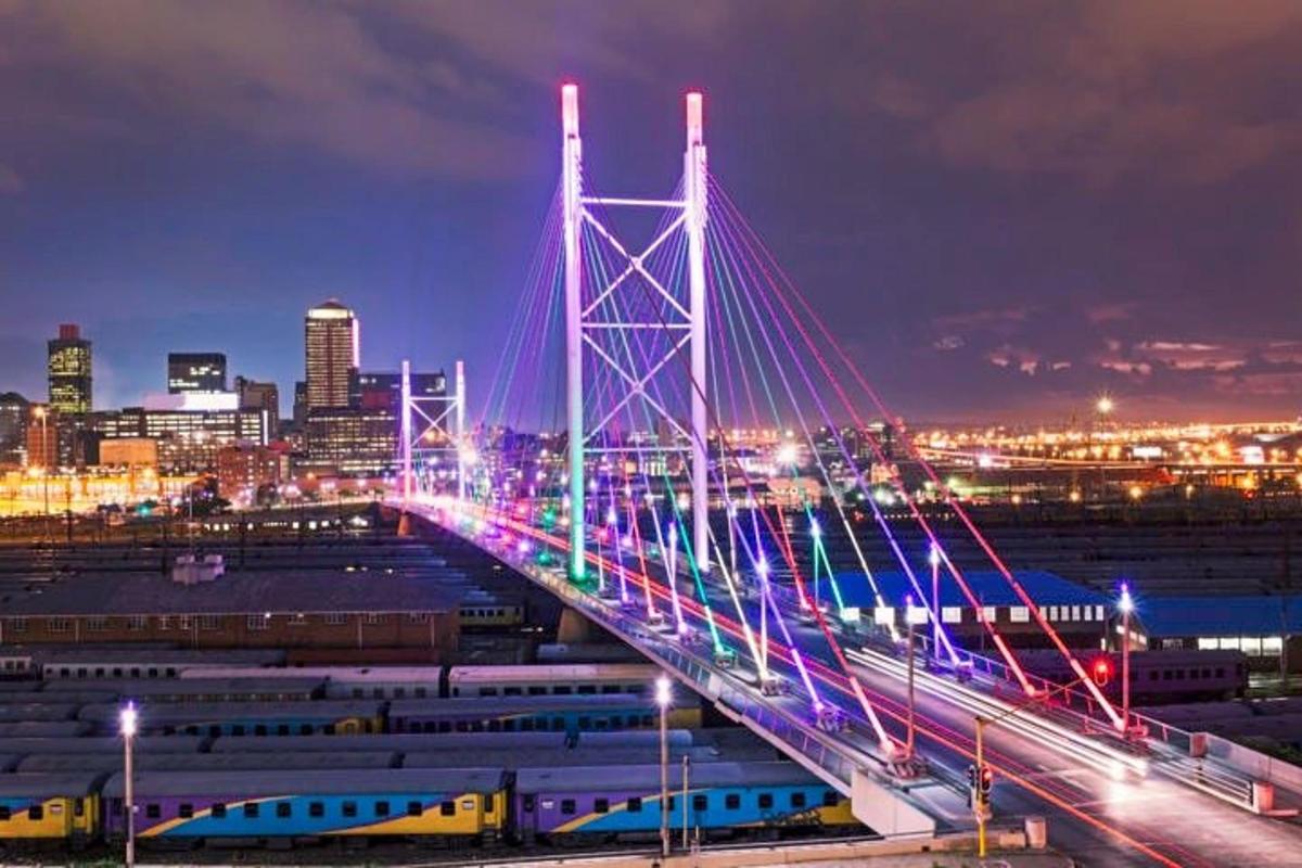 eine Brücke über einer Stadt bei Nacht mit Zügen