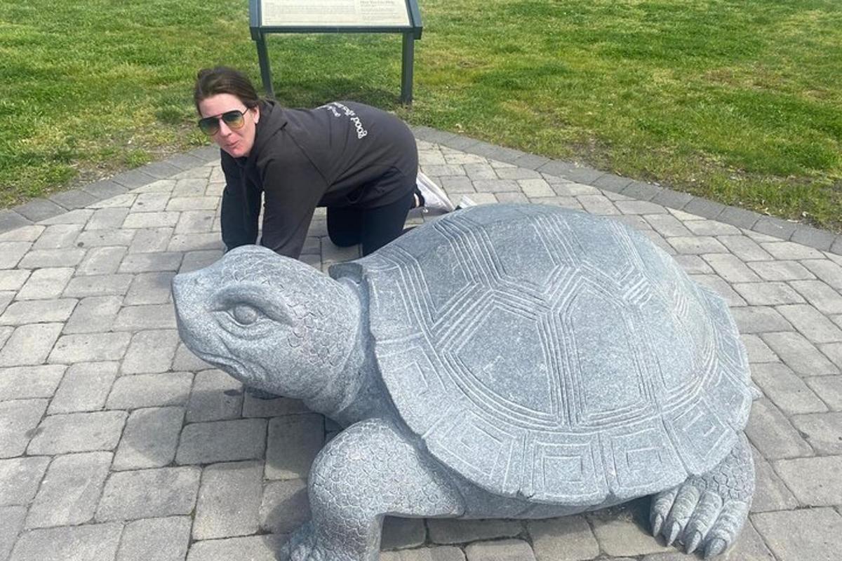 una dona agenollada al costat d'una estàtua d'una tortuga