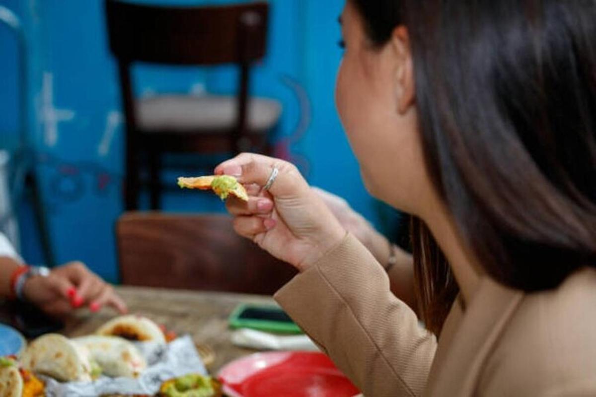 Una mujer sentada en una mesa comiendo un trozo de comida.