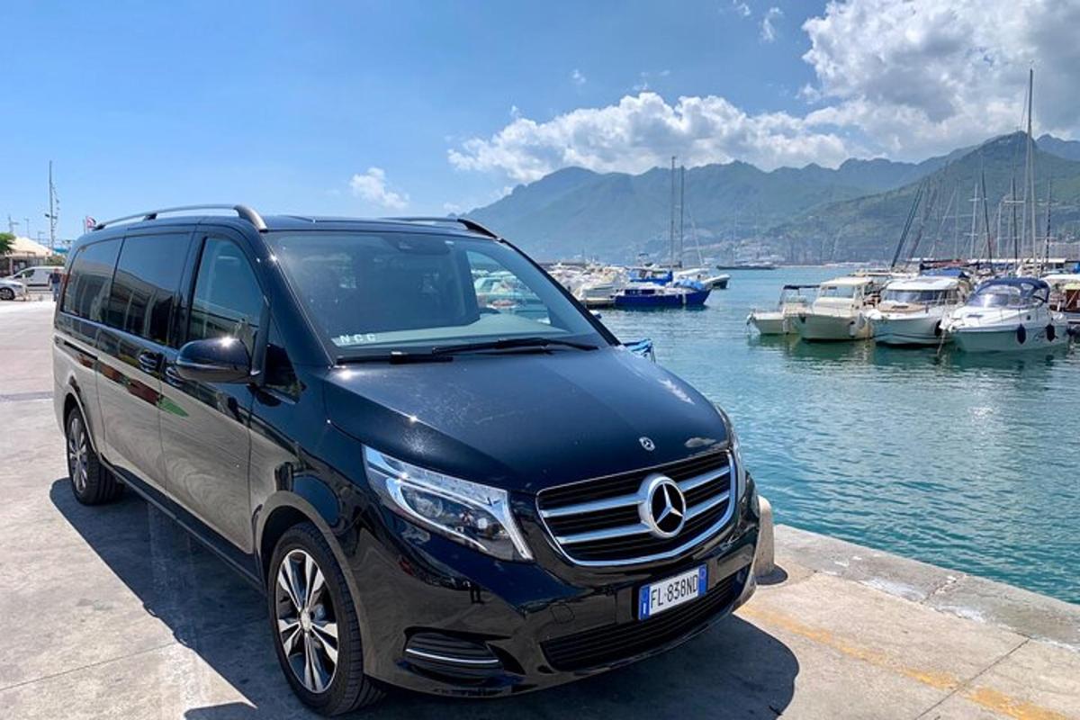 a blue mercedes benz van parked next to a marina